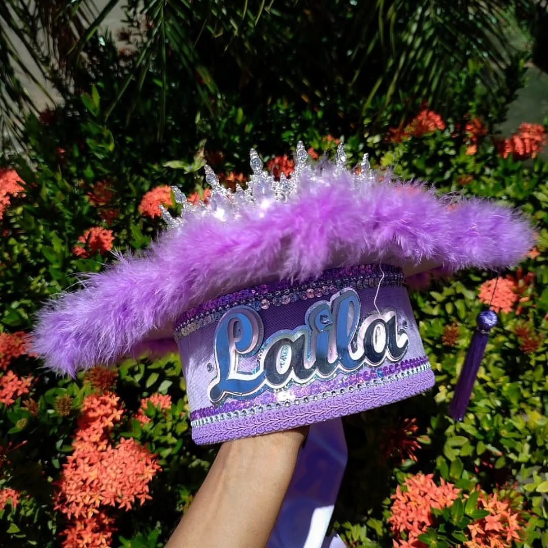 Purple graduation cap with feathers, a tiara, and the name Laila in silver.