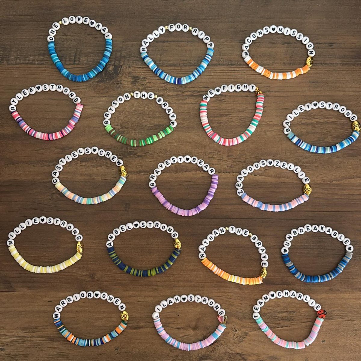 Handmade friendship bracelets with colorful disc beads and letter beads on wooden background