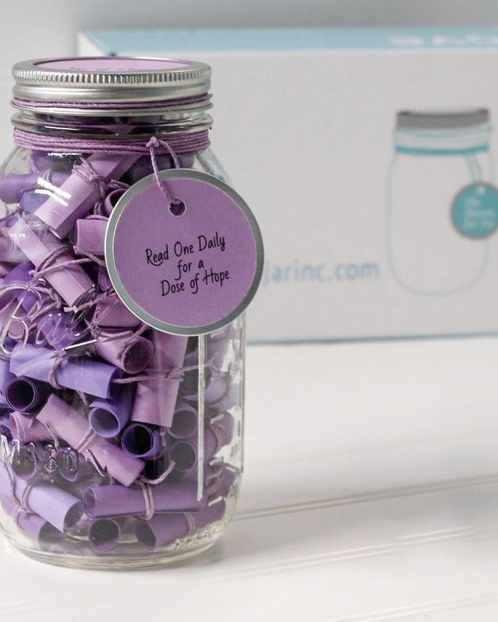 Glass mason jar filled with rolled purple notes and a hope tag.