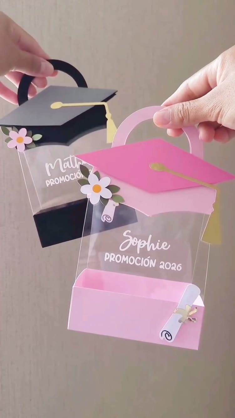 Graduation cap shaped gift bags in black and pink held by two hands.