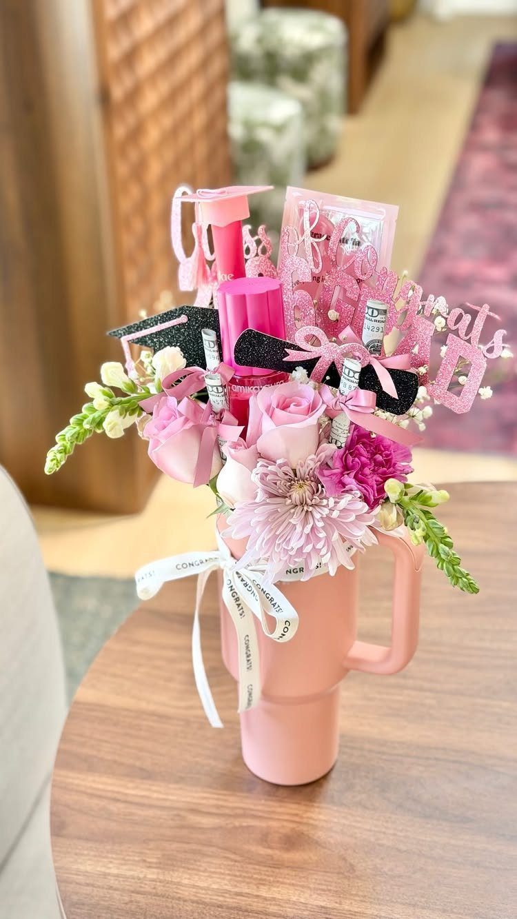 Pink mug filled with roses and graduation decorations on a wooden table