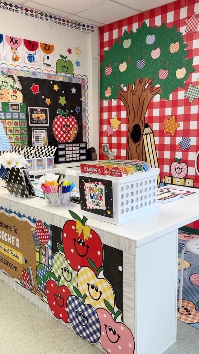 Apple-themed elementary classroom with red checkered walls and a decorated teacher's desk.