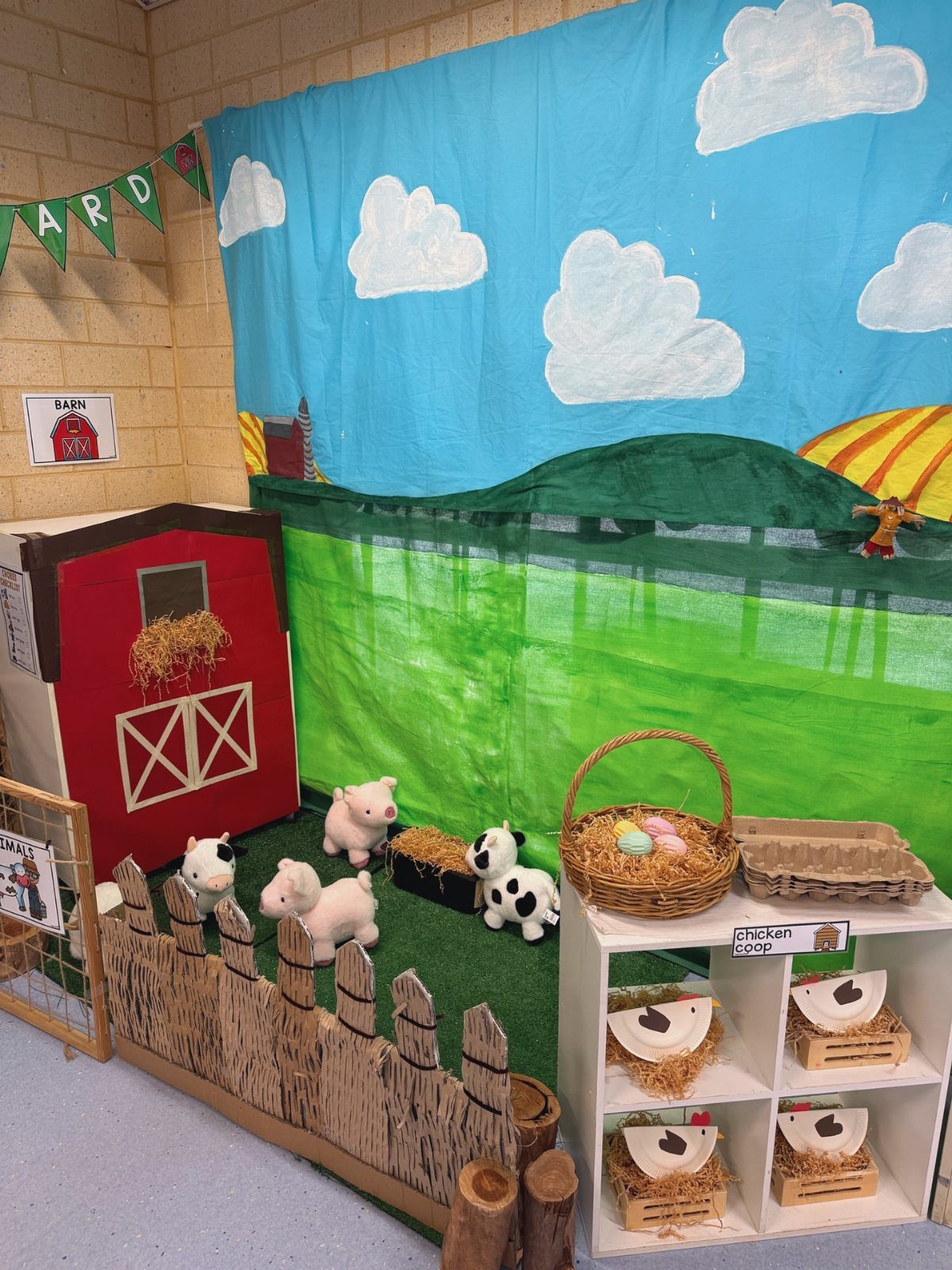 Farm themed classroom display with a red barn, toy animals, and sky backdrop.