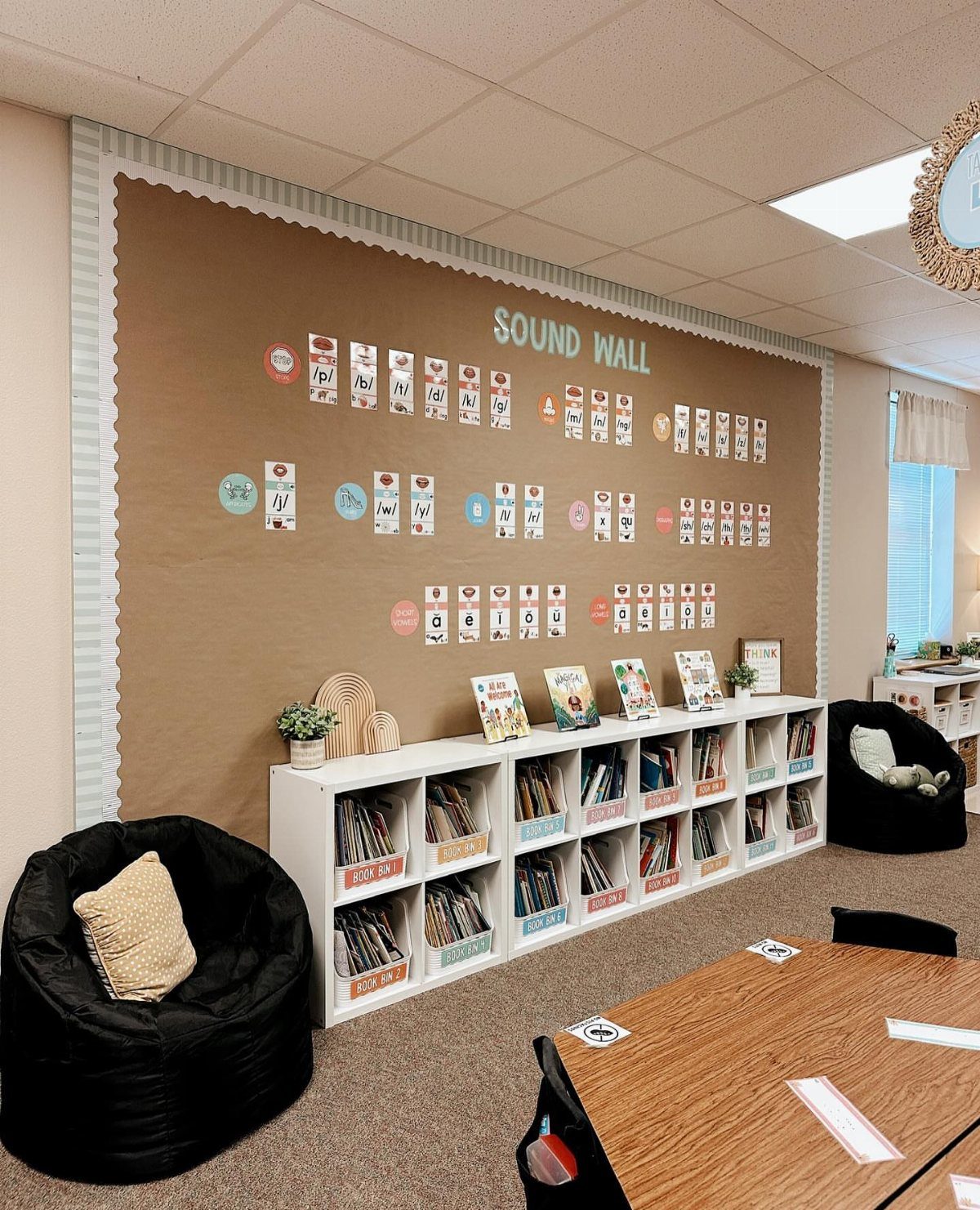 Classroom sound wall and white bookshelves with black beanbag chairs in neutral tones.