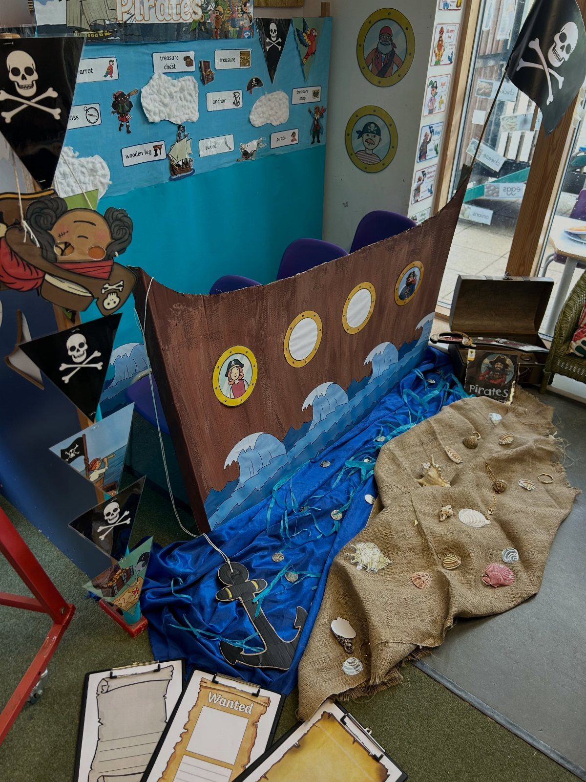 Pirate themed classroom display with a cardboard ship, blue waves, and treasure chest.