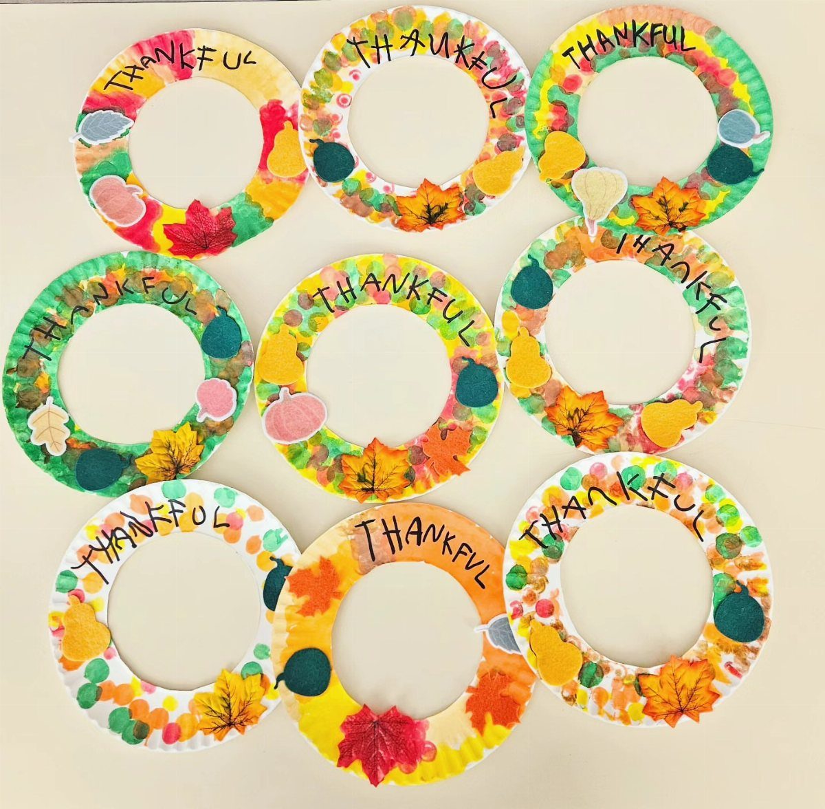 Nine colorful paper autumn wreaths decorated with leaves and the word THANKFUL.