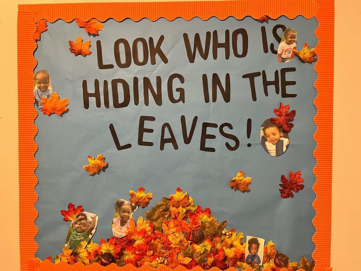 Fall-themed bulletin board with blue background, autumn leaves, and photos of students.