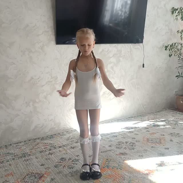 Young girl in white dress and black shoes posing for first day outfit.