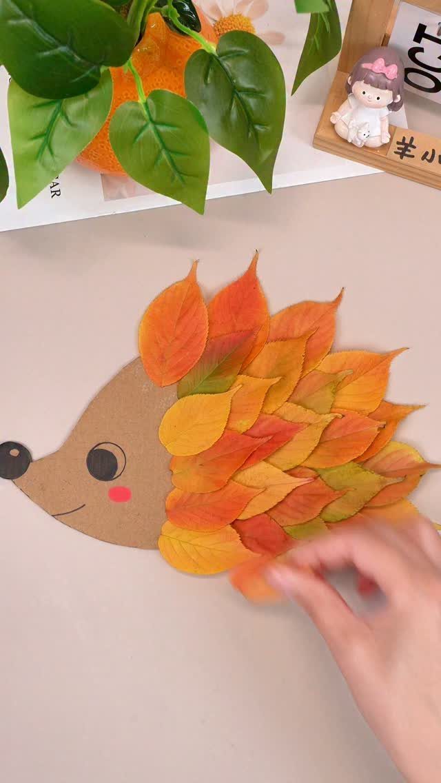 Hedgehog craft made from brown cardboard and colorful autumn leaves on a table.