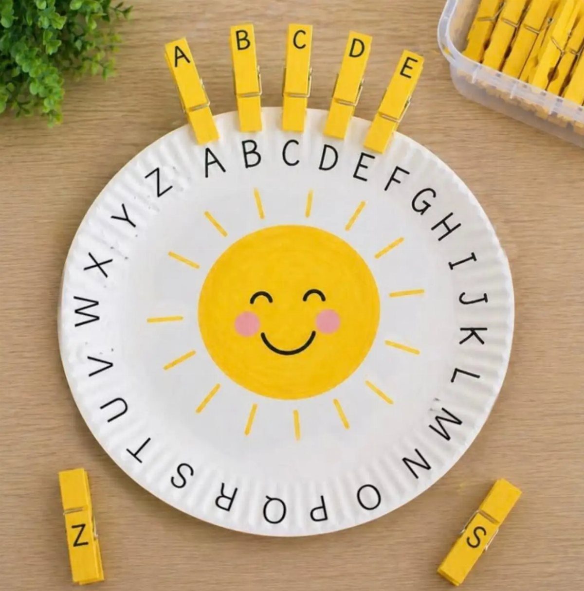 Alphabet matching game with yellow clothespins on a sun-themed paper plate.