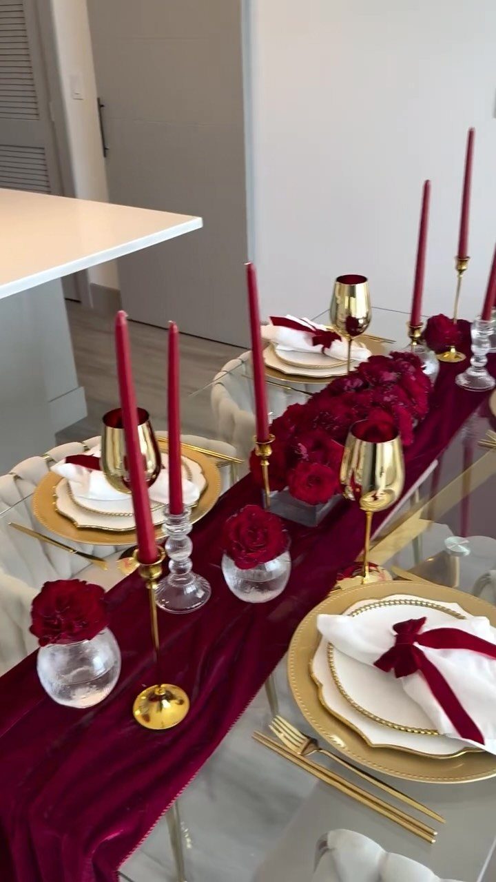 Formal banquet table with burgundy velvet runner, red roses, and gold dinnerware.
