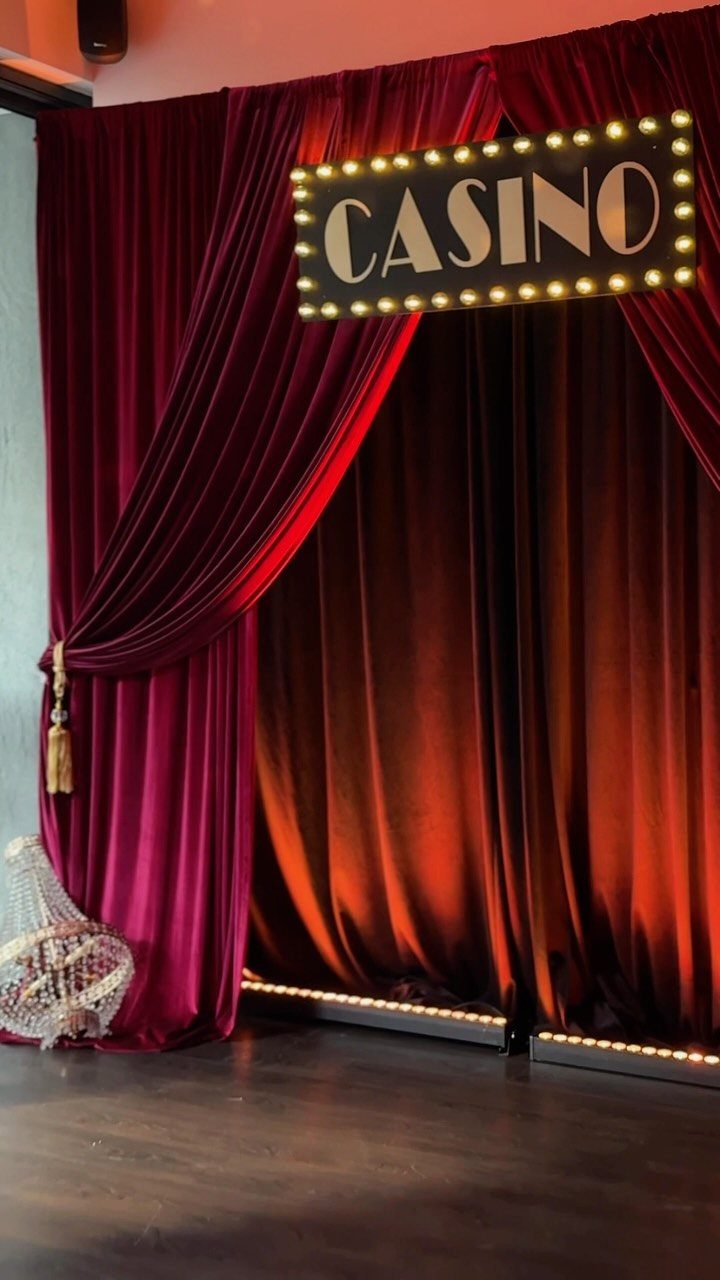 Red velvet curtains with an illuminated Casino marquee sign creating a gala entrance.