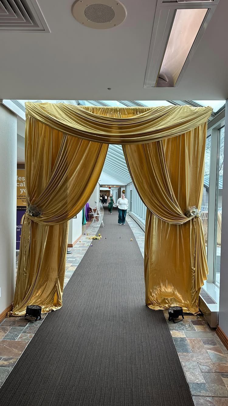 Gold satin curtain archway over a brown carpet runner in a hallway.