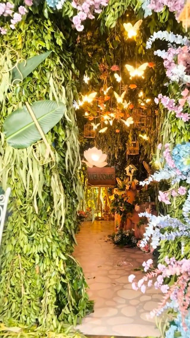 Floral archway with glowing butterfly lights leading into a decorated gala event space