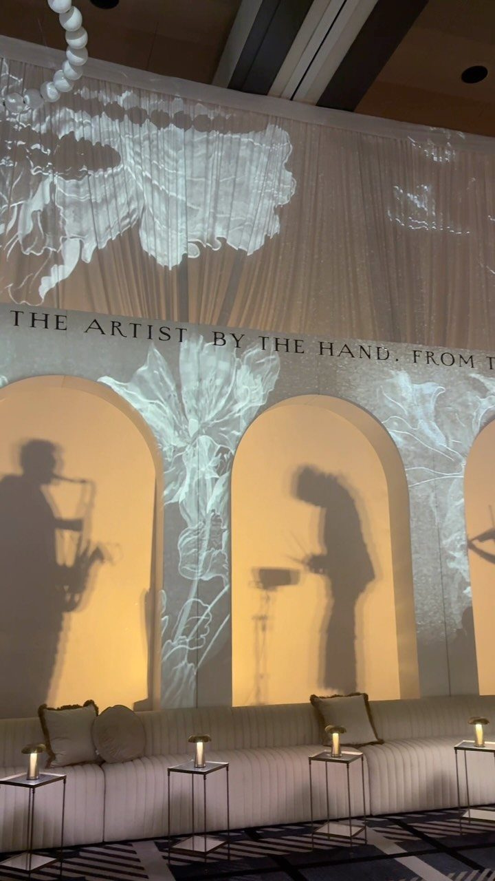Elegant gala lounge with white sofa and artistic projections of musicians on curtains.