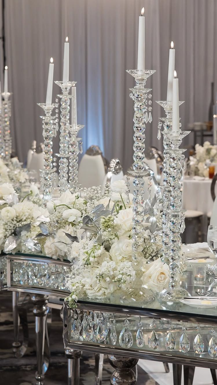 Mirrored banquet table with white flowers and crystal candelabras under soft blue lighting
