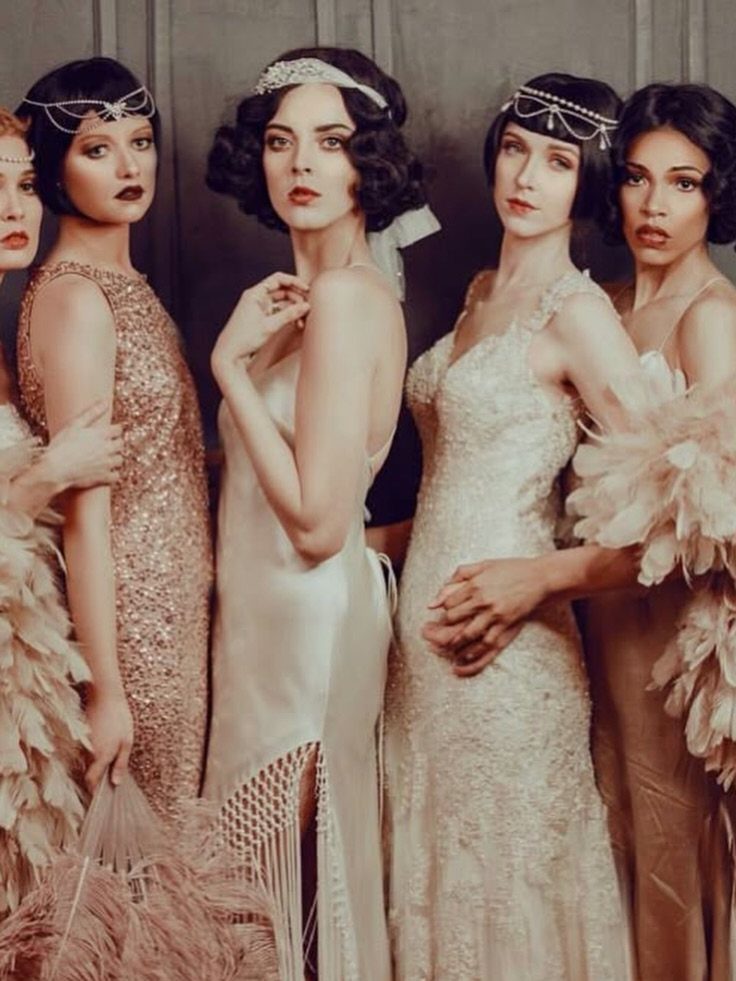 Five women in 1920s flapper dresses and headbands posing for a portrait.
