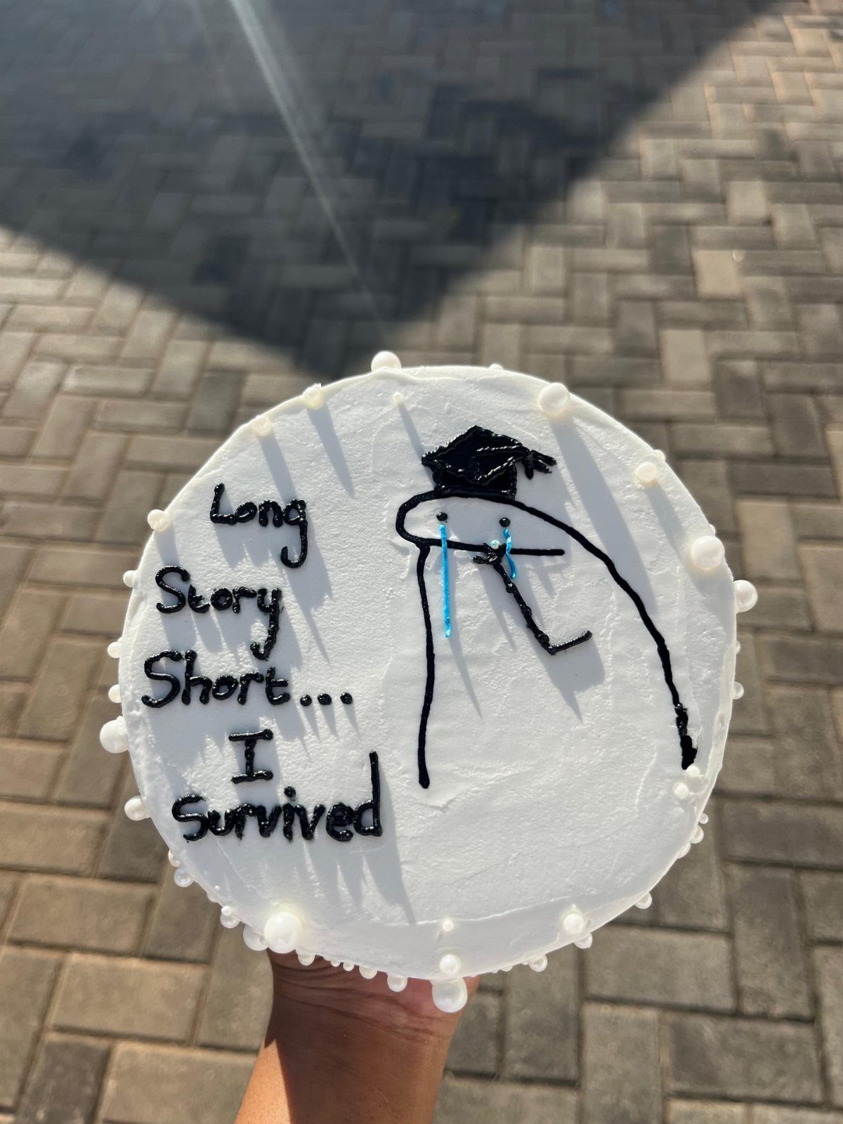 White frosted cake with a stick figure in a graduation cap and sassy text.