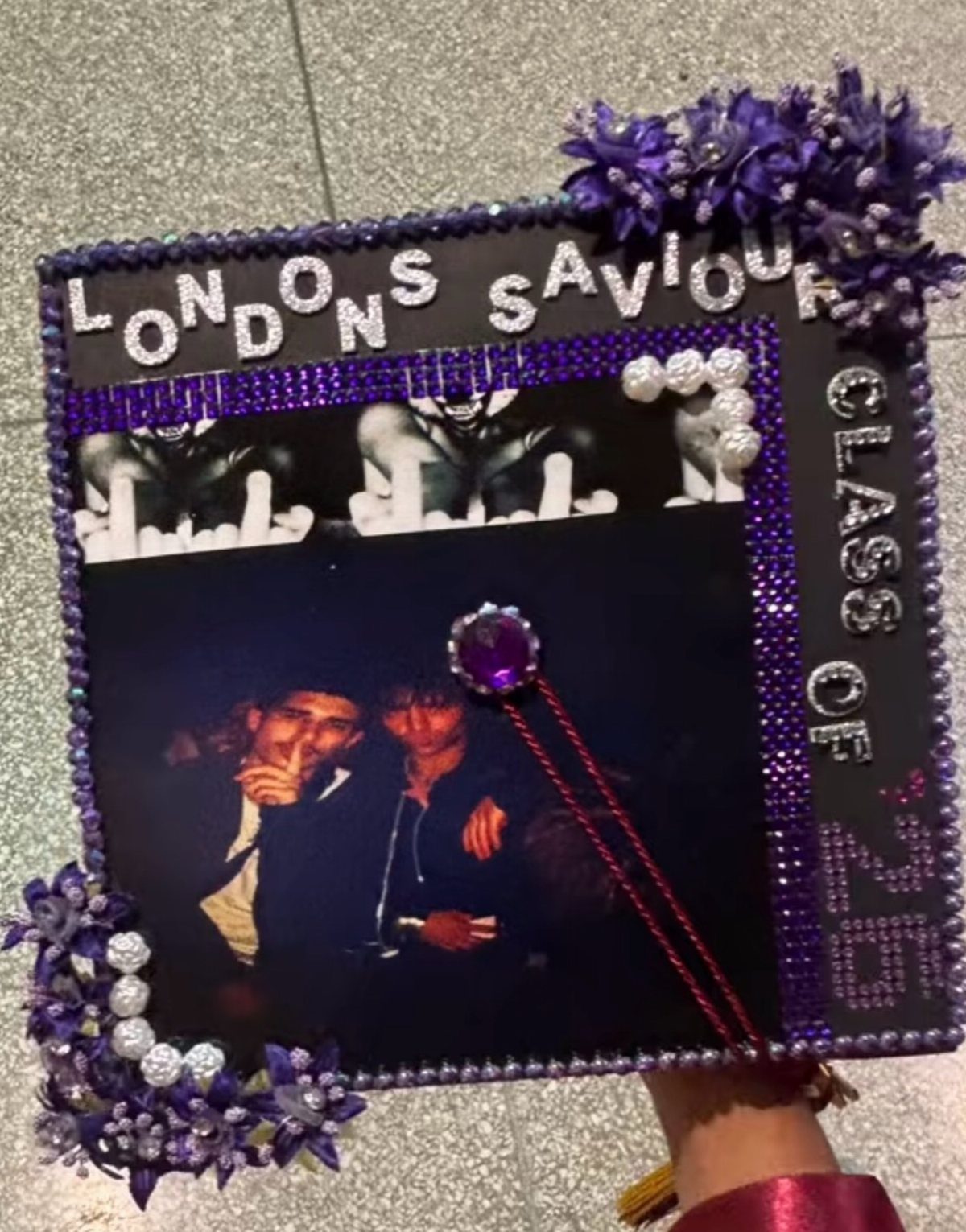 Decorated purple graduation cap with rhinestones, faux flowers, and personal photographs.