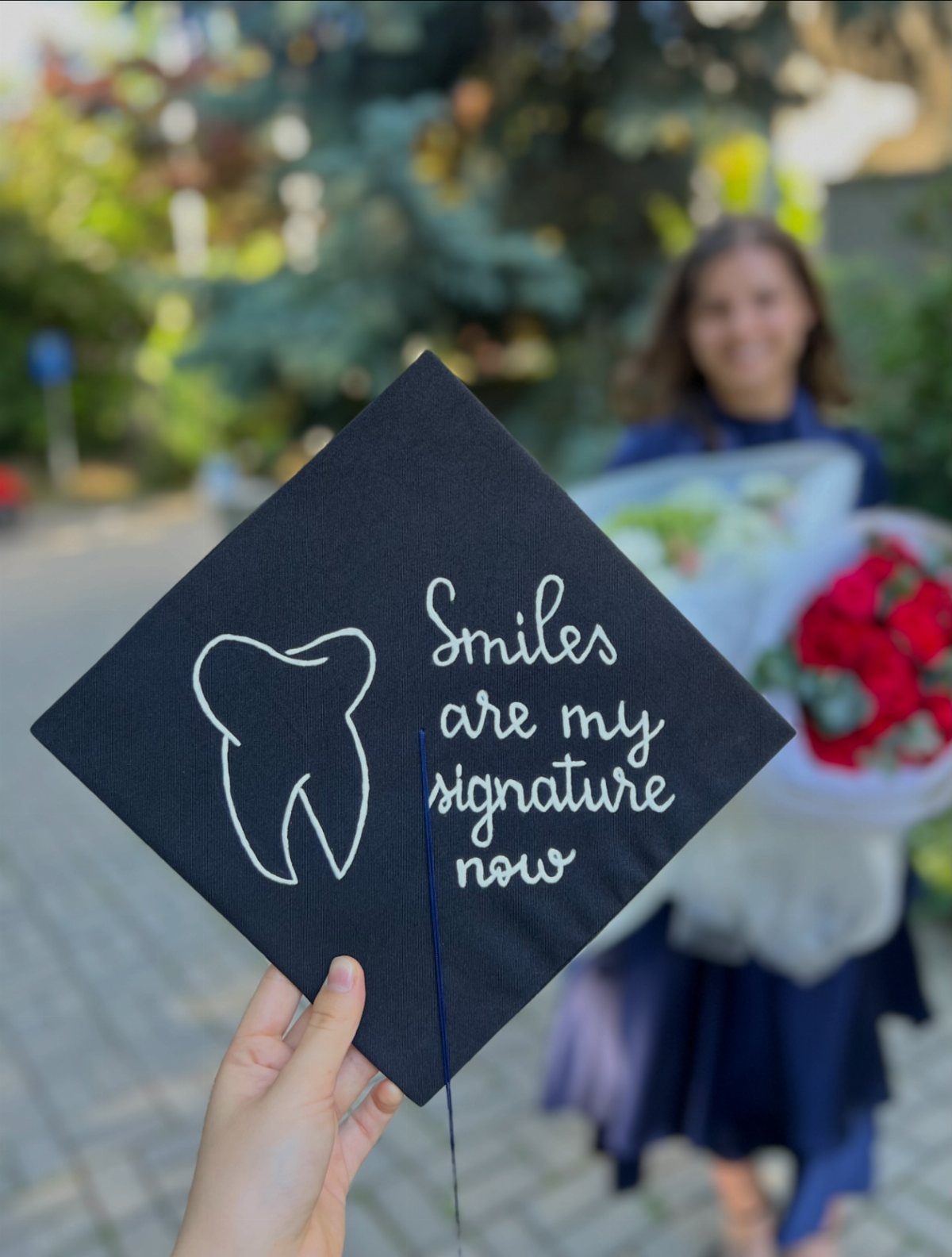 Graduation cap decorated with a white tooth drawing and dental-themed quote.