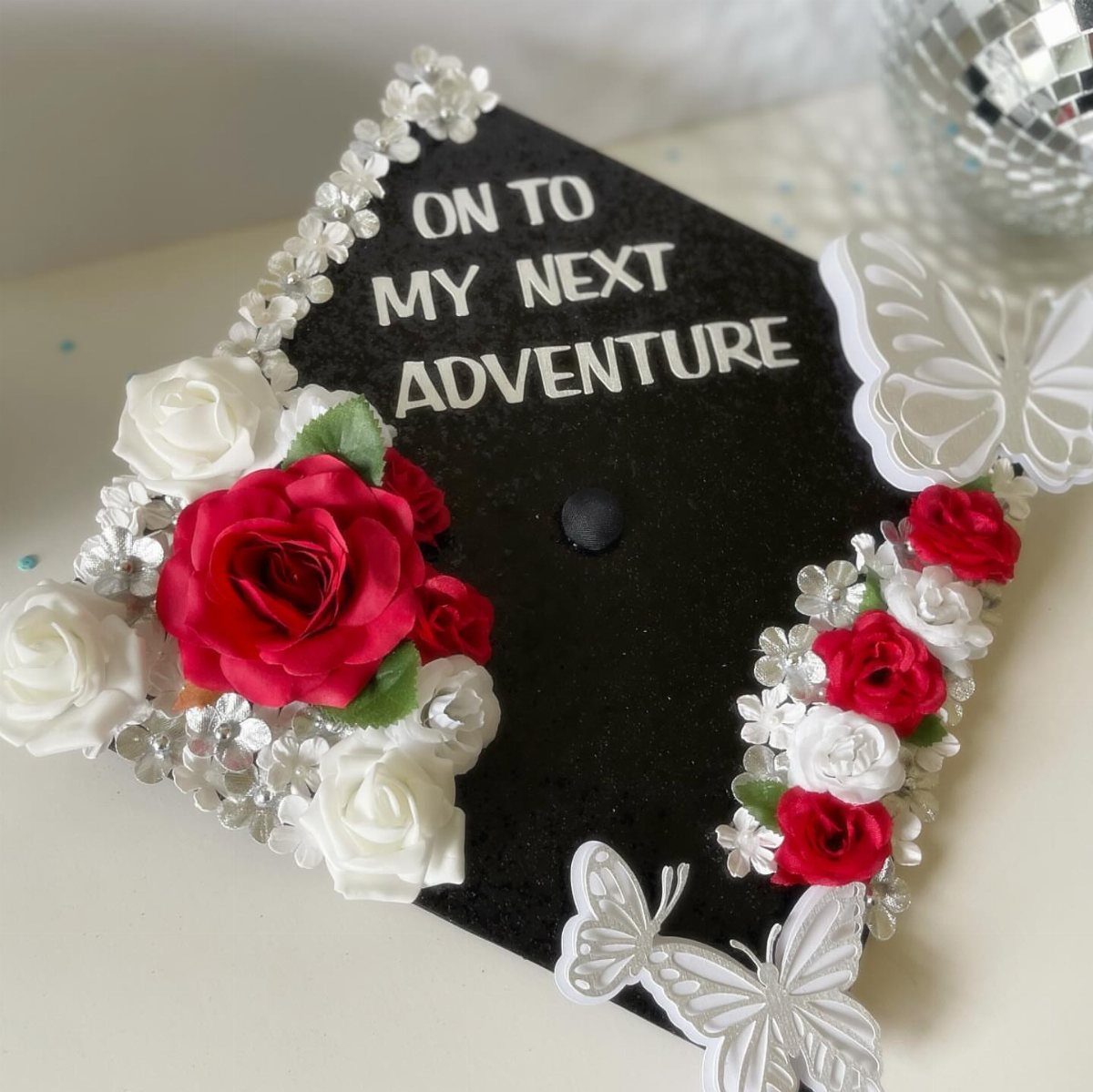 Graduation cap decorated with red and white roses, silver rhinestones, and inspirational text.