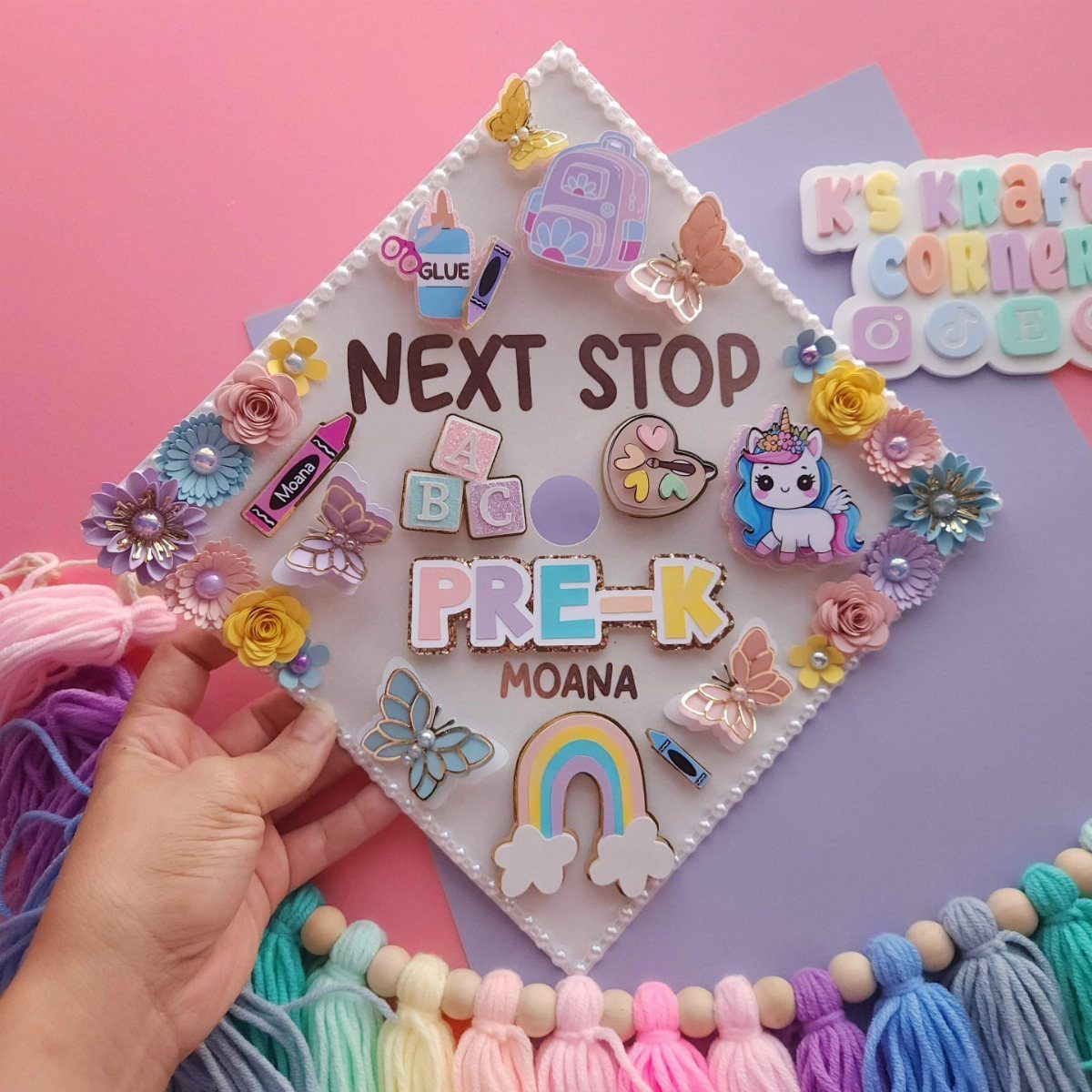 Decorated graduation cap with colorful faux flowers, butterflies, and Pre-K text.