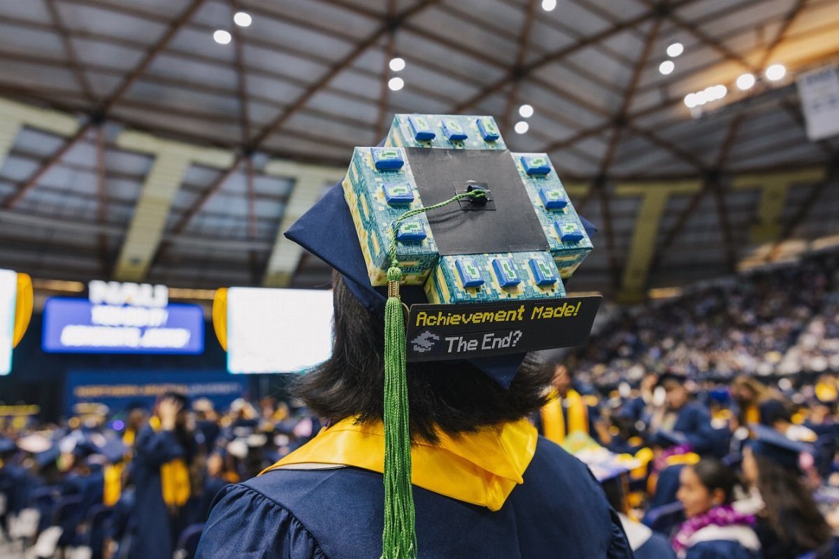 Graduation cap decorated with Minecraft grass blocks and a pixelated achievement sign.