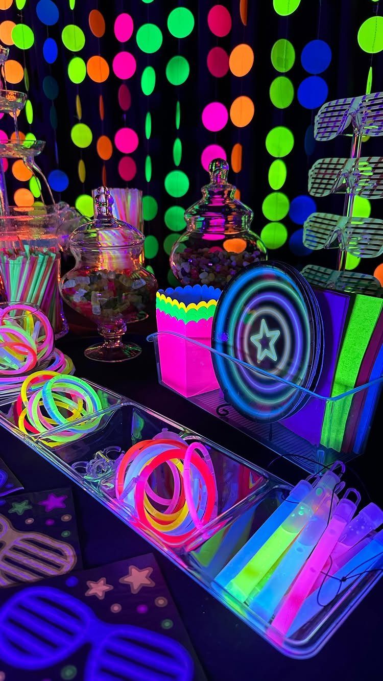 Neon glow sticks and bracelets on a table with colorful circular backdrop.