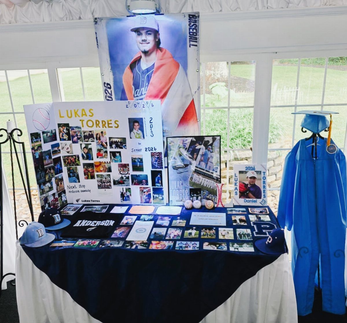 Graduation memory table with photos, baseball caps, and a blue graduation gown.