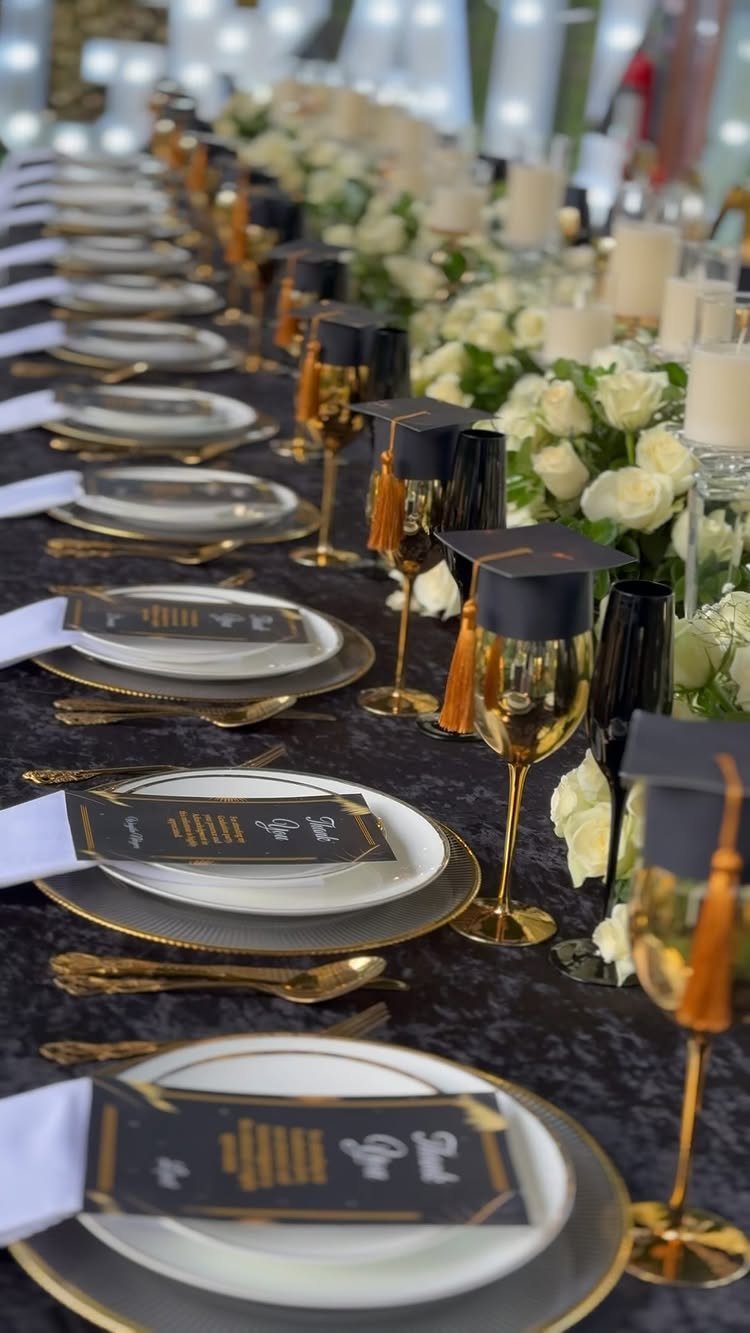 Elegant graduation party table setting with black and gold decor and white roses.