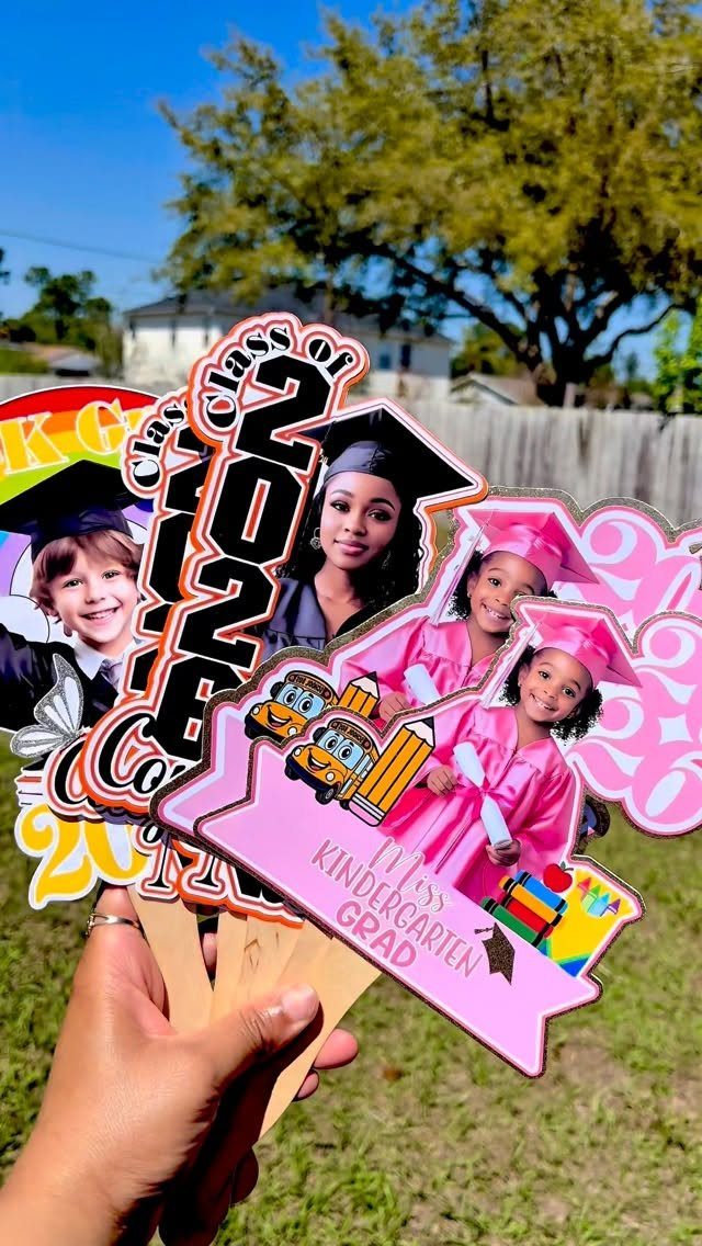Custom graduation photo props on sticks featuring graduates of various ages outdoors.