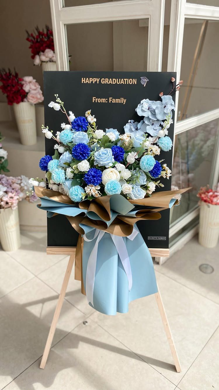 Blue and white flower bouquet on an easel with a graduation sign.