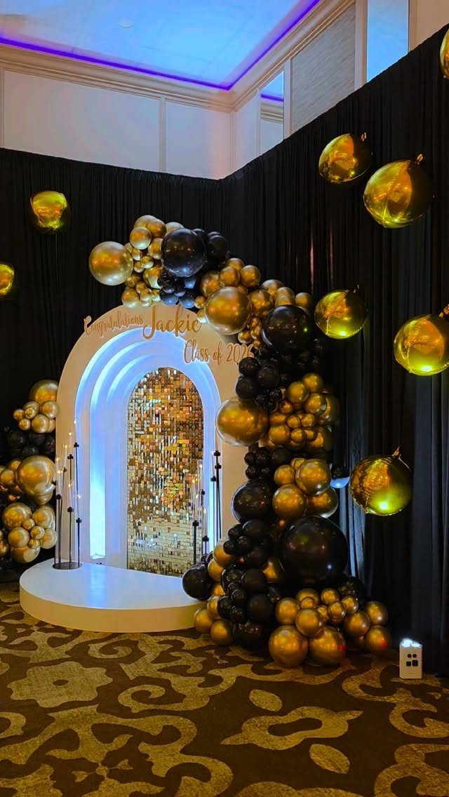 Gold and black balloon arch framing a white arched entryway with sequin backdrop.