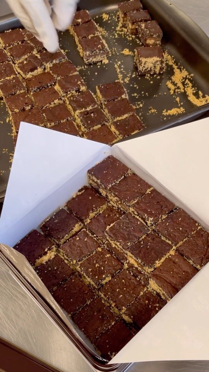 Chocolate peanut butter brownie bites arranged in a box and on a baking sheet.