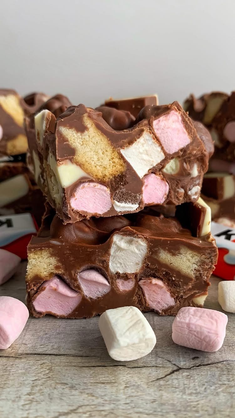 Chocolate rocky road bars with marshmallows and biscuits on a wooden surface.