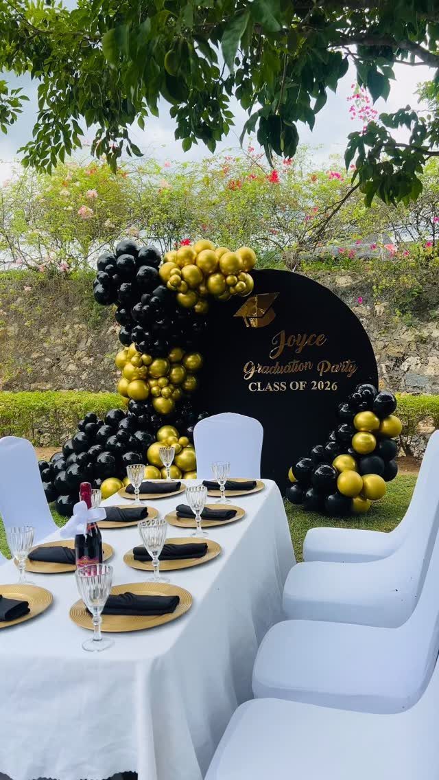 Graduation party setup with black and gold balloons, a circular backdrop, and decorated table.