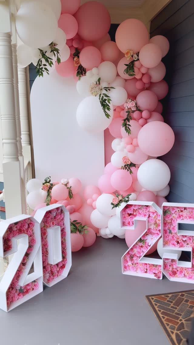 Pink and white balloon arch with floral 2025 numbers for a graduation party.