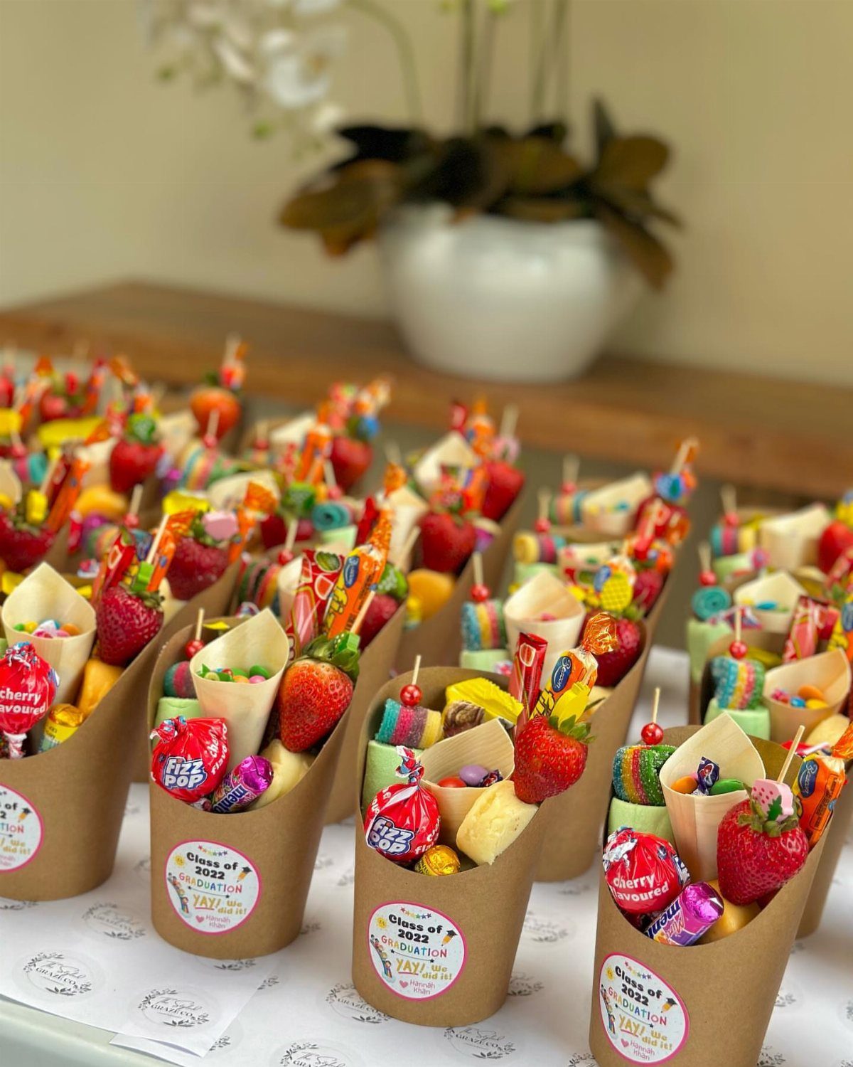 Candy and strawberry treats in brown paper cones for a 2022 graduation party.