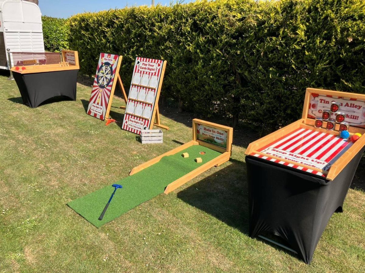 Carnival-style lawn games set up on a grassy lawn next to a hedge.