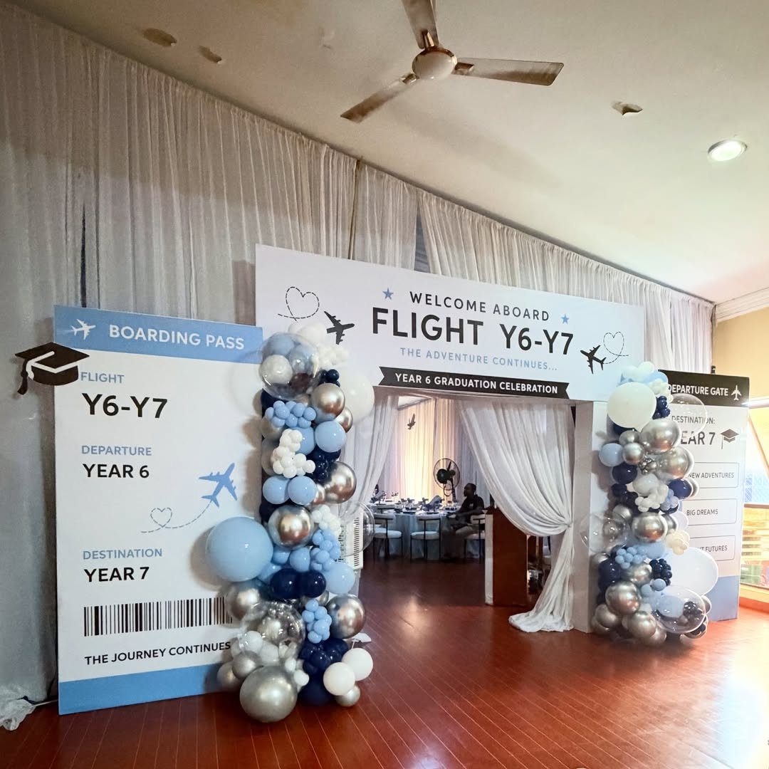 Travel-themed graduation entrance with boarding pass sign and blue balloon arches.