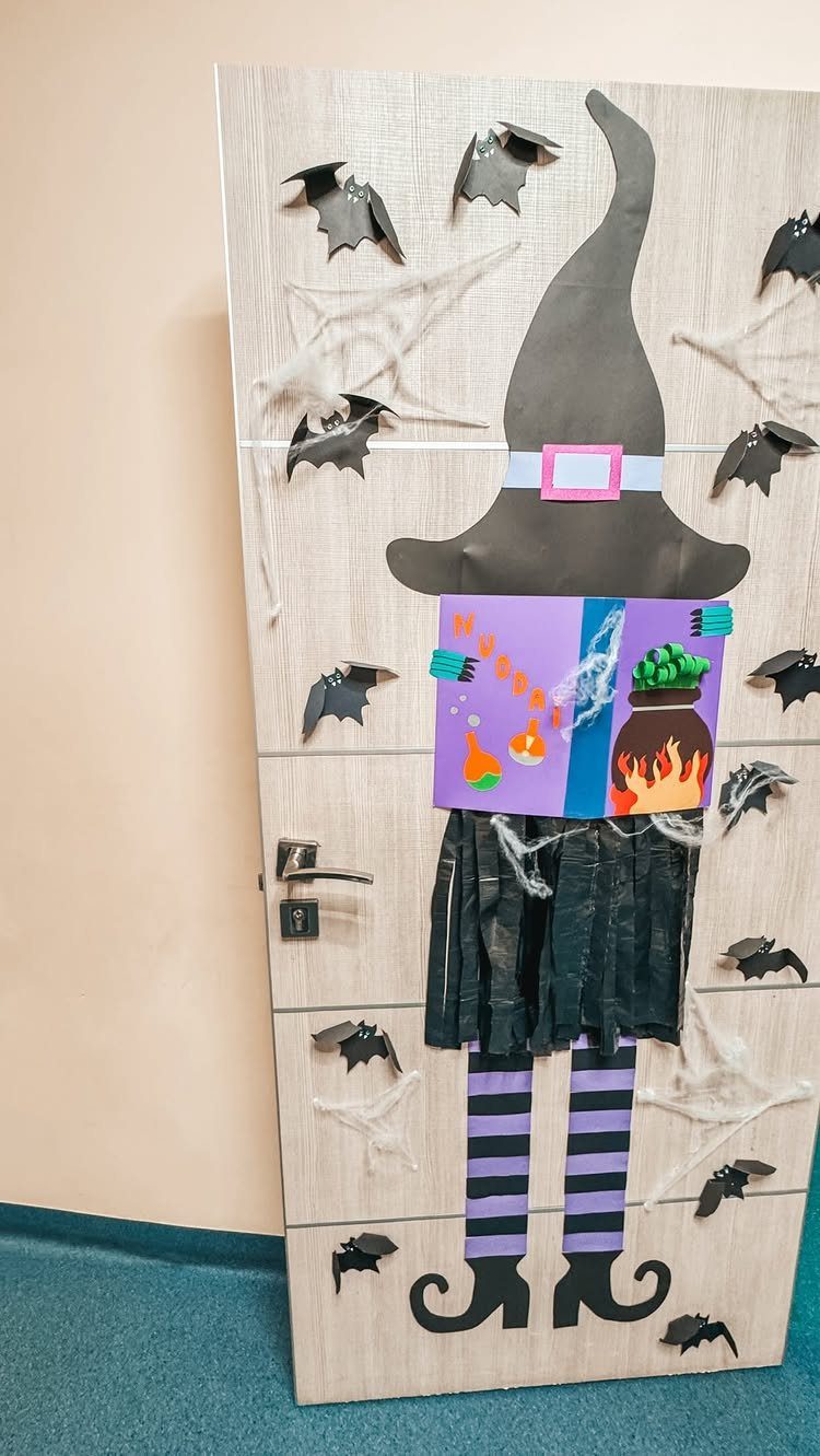 Witch figure decoration on a classroom door with bats and spider webs