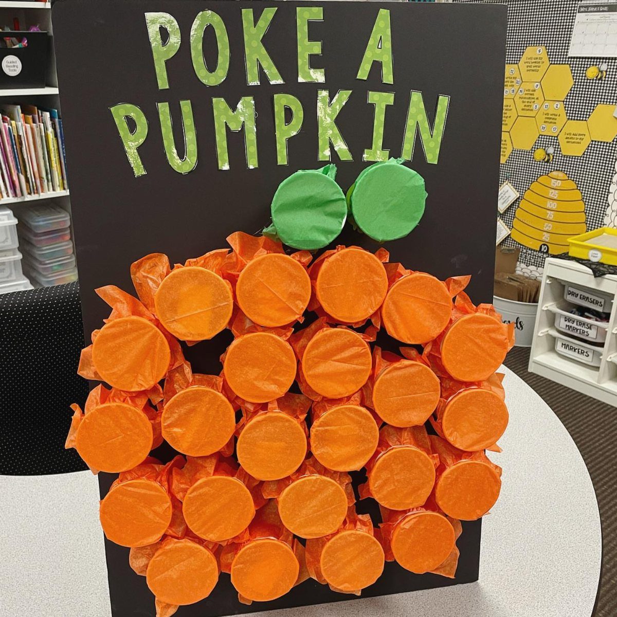 Poke a Pumpkin game board with orange tissue paper pumpkins in a classroom