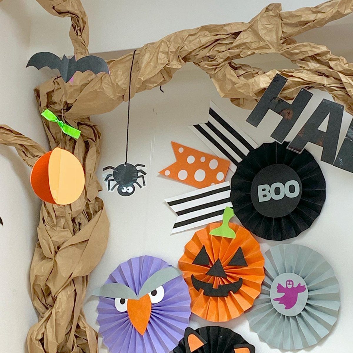 Halloween wall decorations with a paper tree, colorful paper fans, and striped banners.