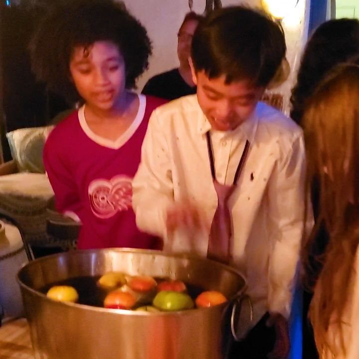 Children standing around a metal tub of floating apples for apple bobbing.