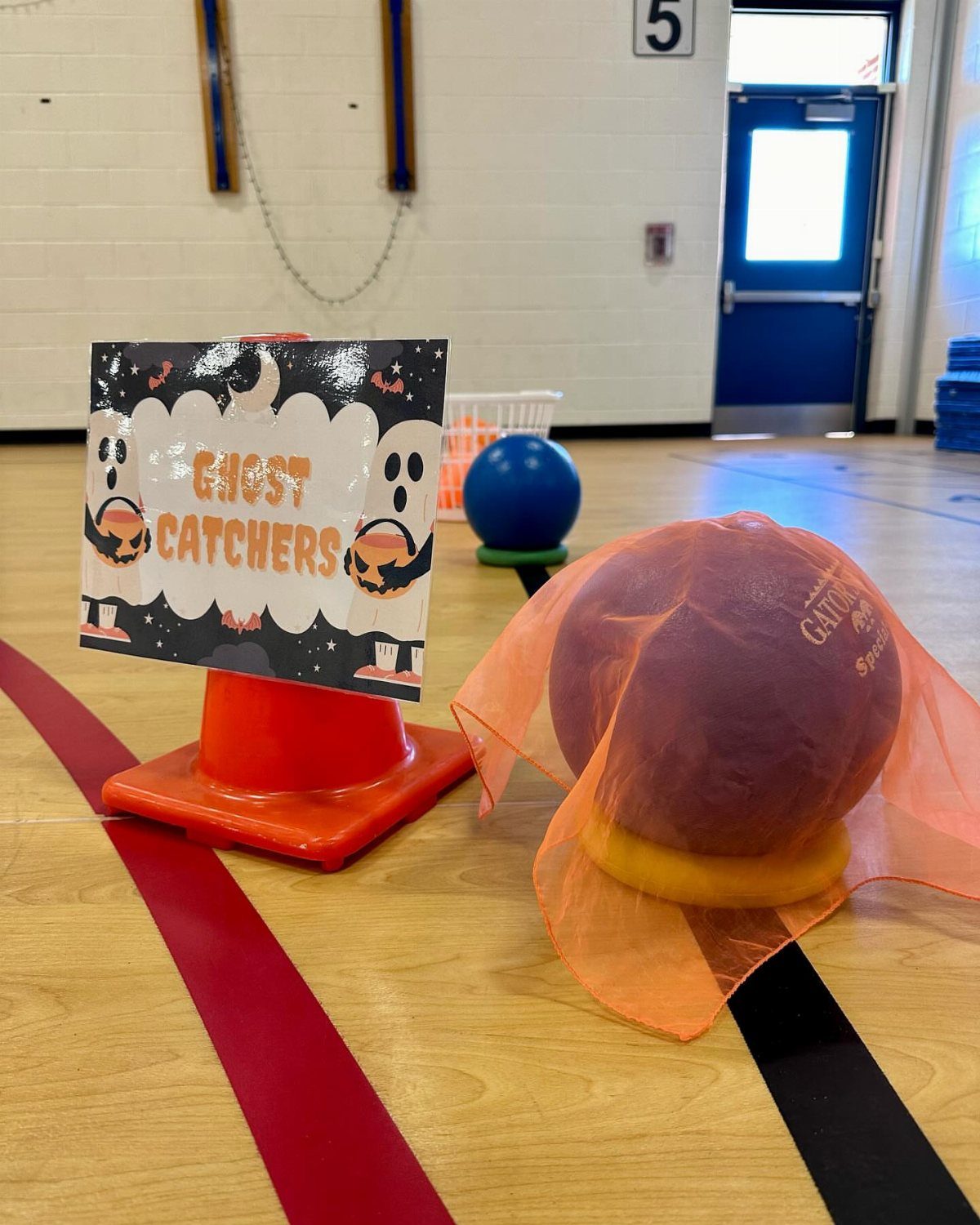 Ghost Catchers game setup with balls and a sign on a gym floor