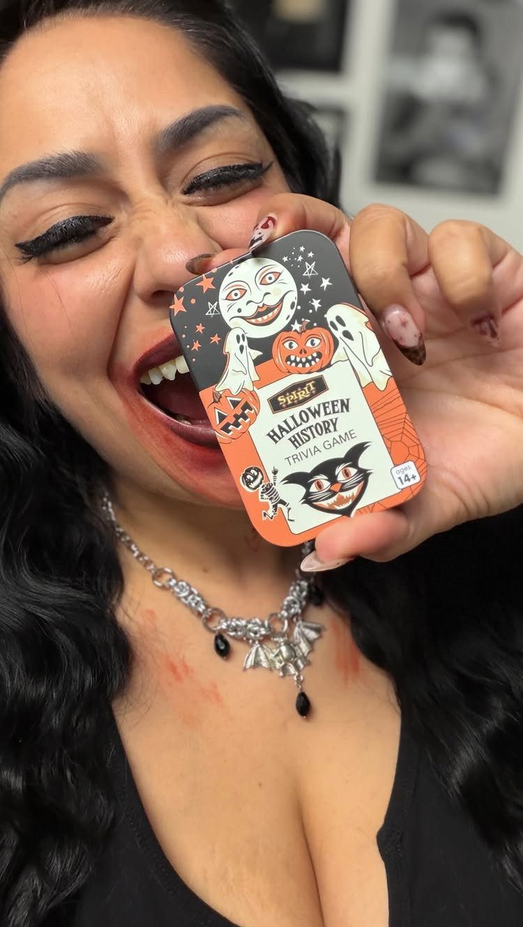 Woman holding a Halloween History Trivia Game box near her open mouth.