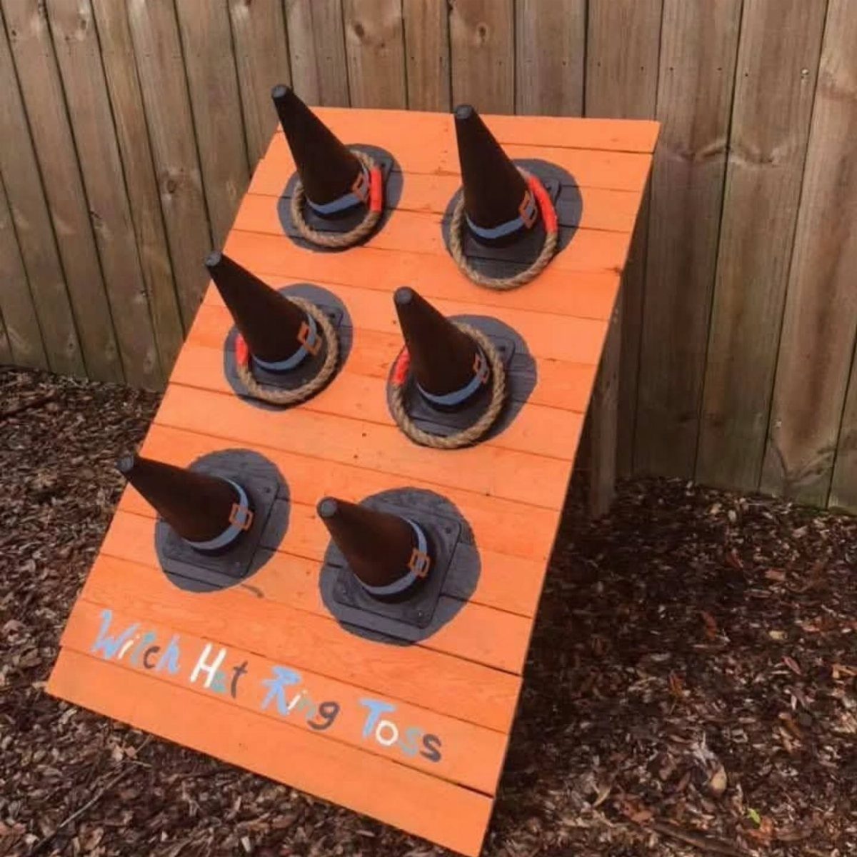 Witch hat ring toss game on an orange wooden board with rope rings.