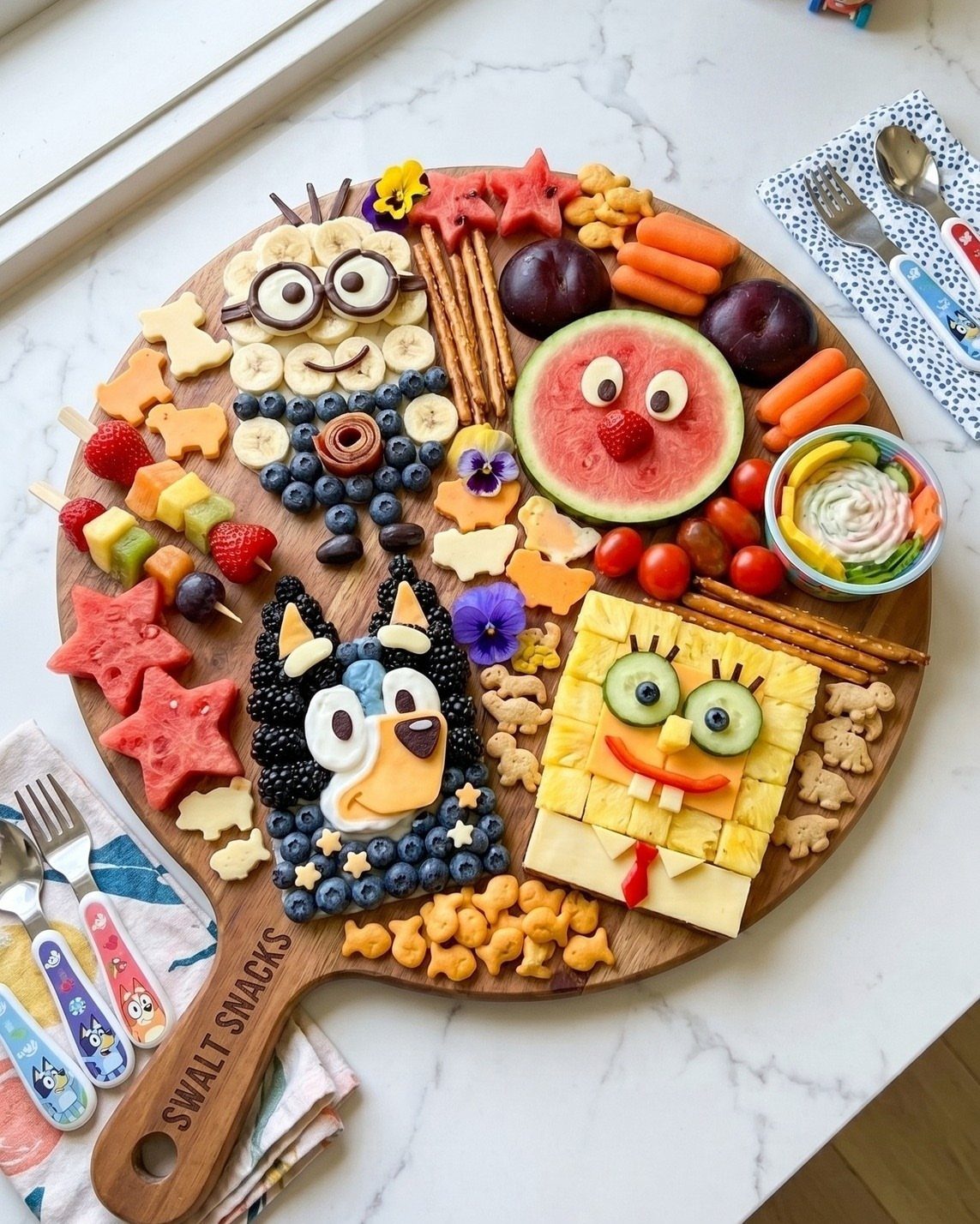 Food platter with characters made from fruit, cheese, and vegetables on wooden board.