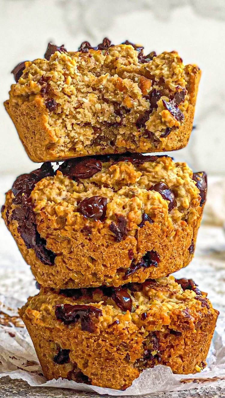 Three stacked chocolate chip oat muffins with the top one sliced open.