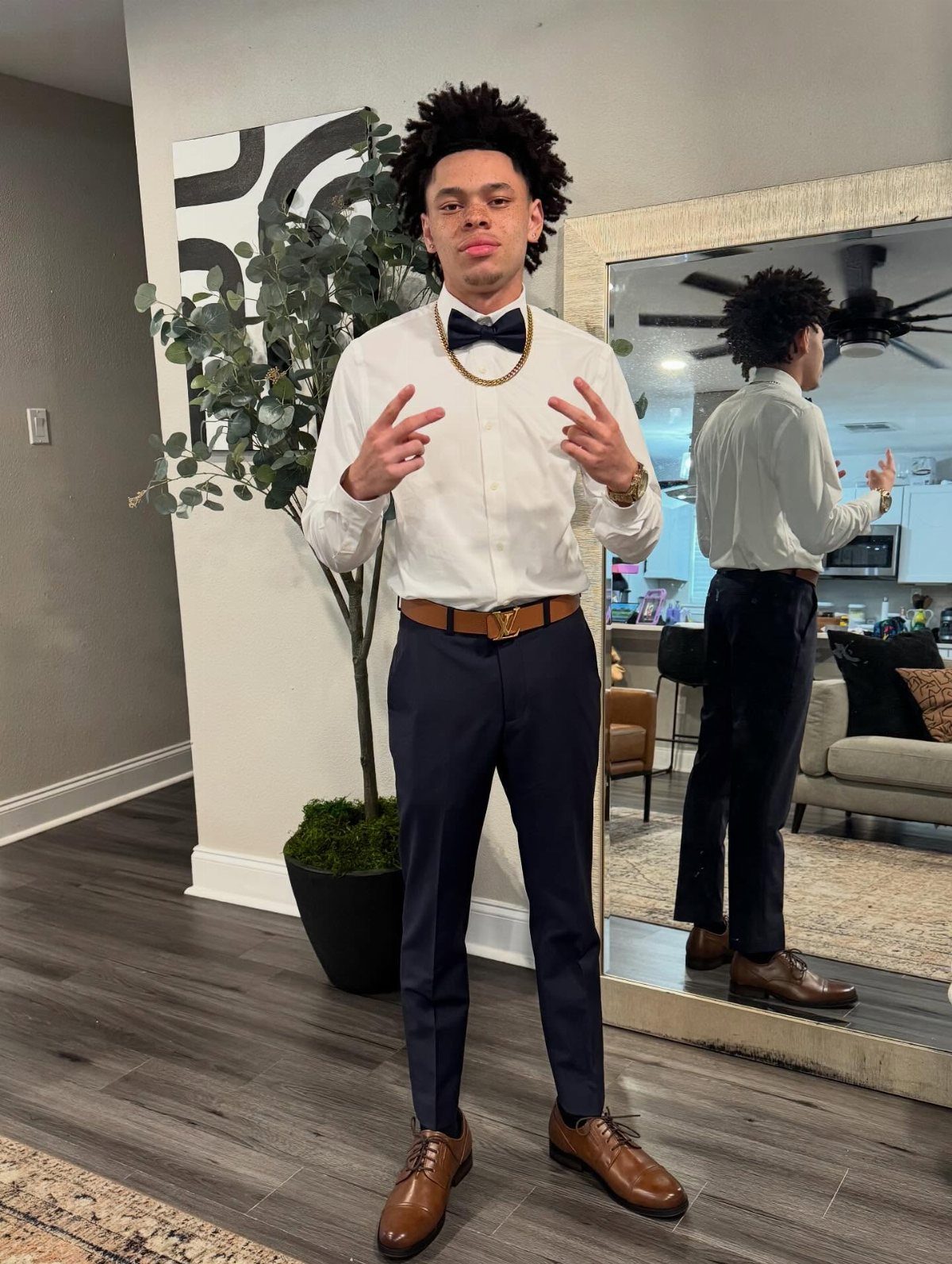 Young man wearing a white dress shirt, black bow tie, and navy dress pants.